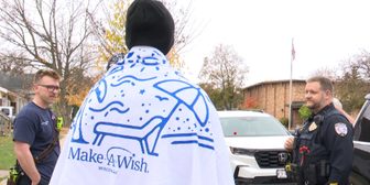 Ayden Leonhardt, seen from behind wearing a Make-A-Wish Wisconsin blanket, talks with Wausau police and fire crews during his send-off